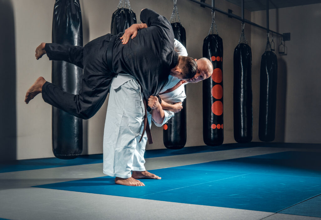 Dois lutadores treinando uma projeção no tatame da academia